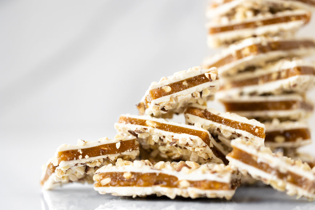 Sugar-Free English Toffee coated in white chocolate – Handcrafted, buttery, and crunchy toffee made with real butter, maltitol, and roasted almonds. Small-batch, no added sugar, and no corn syrup. Close up view.